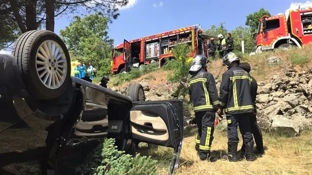 Imagen de archivo de un accidente de tráfico en carretera con un vehículo caído por un terraplén y la intervención de bomberos