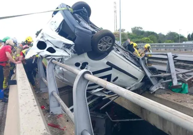 Aparatoso accidente de tráfico: un coche acaba volcado y colgando sobre un puente