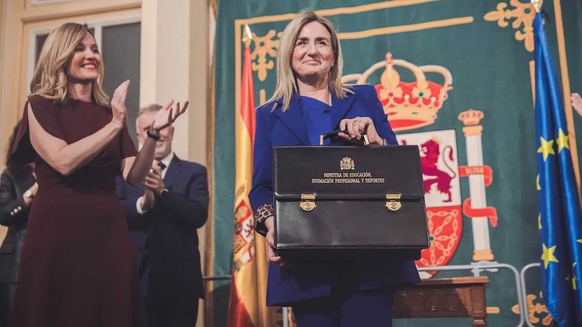 Milagros Tol&oacute;n sostiene la cartera de Educaci&oacute;n, Formaci&oacute;n Profesional y Deportes tras el acto de traspaso, con Pilar Alegr&iacute;a aplaudiendo al fondo, en el Ministerio de Educaci&oacute;n