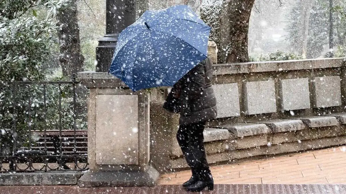 Imagen de archivo de un vecino resguard&aacute;ndose de la nieve ante la ca&iacute;da de una nevada en Cuenca. EFE/Jos&eacute; del Olmo