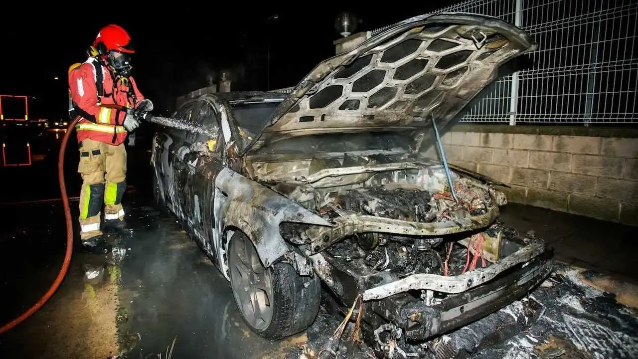 En la imagen de archivo un bombero extingue el incendio de veh&iacute;culo calcinado tras salir ardiendo, incendiado