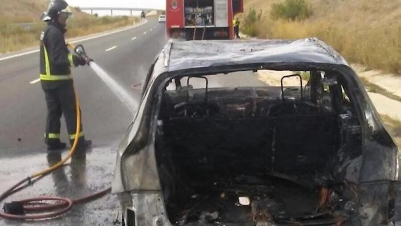 Imagen de archivo de un bombero extinguiendo un vehículo incendiado
