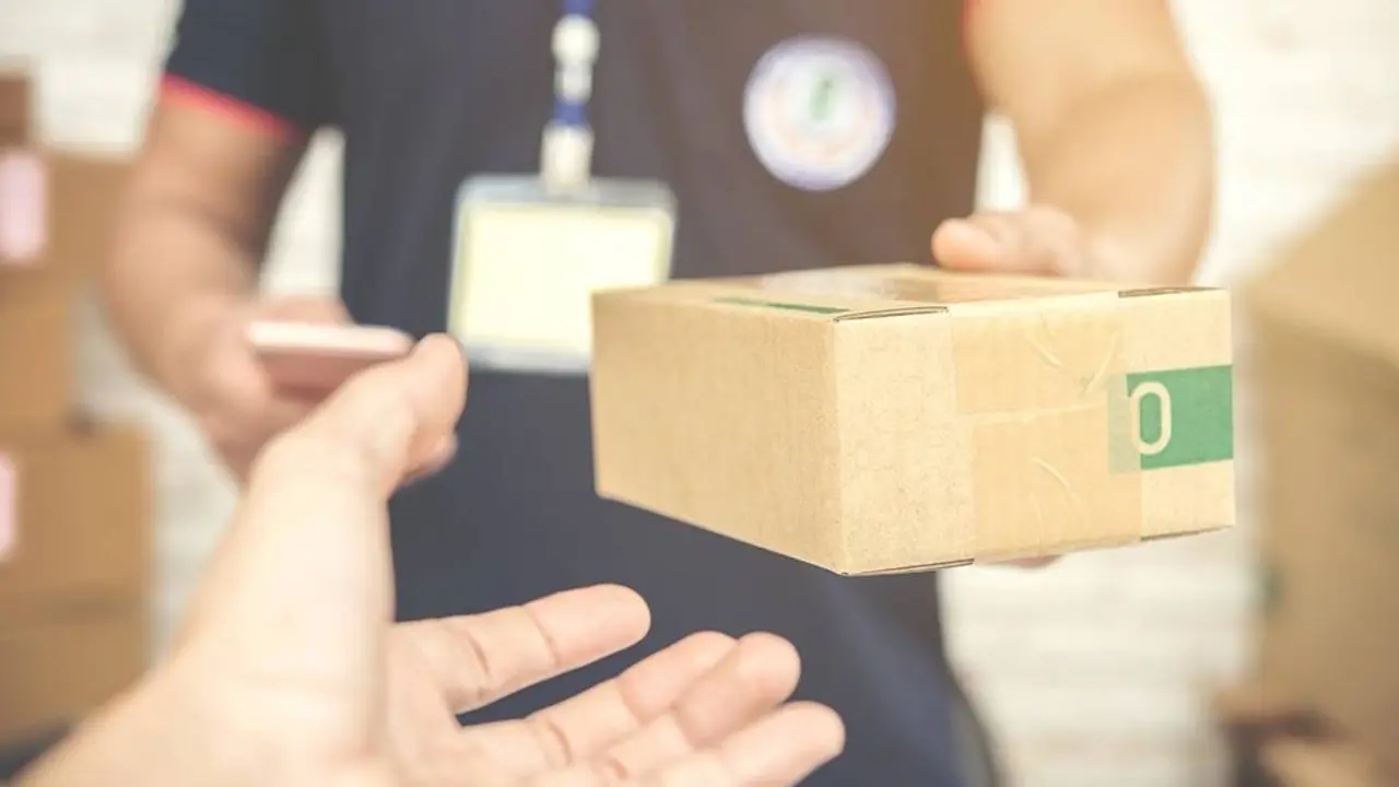 delivery man smiling and holding a cardboard box