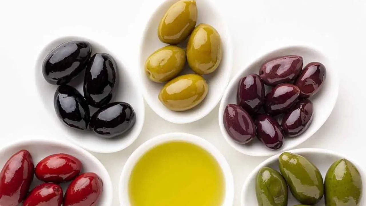 close-up-red-black-yellow-purple-olives-on-plates-with-leaves-and-olive-saucer
