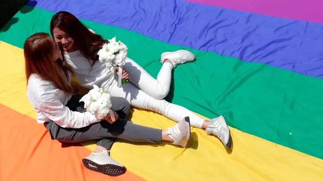 Una pareja de mujeres recién casada se sienta sobre una bandera LGTBI - Archivo/EFE/Ritchie B. Tongo