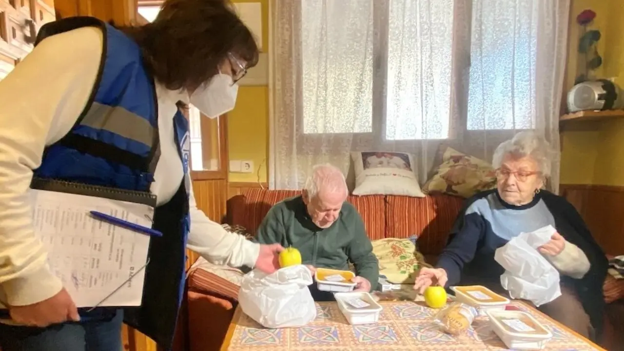 En la imagen de archivo dos usuarios del programa de apoyo nutricional a mayores reciben en su domicilio su comida diaria