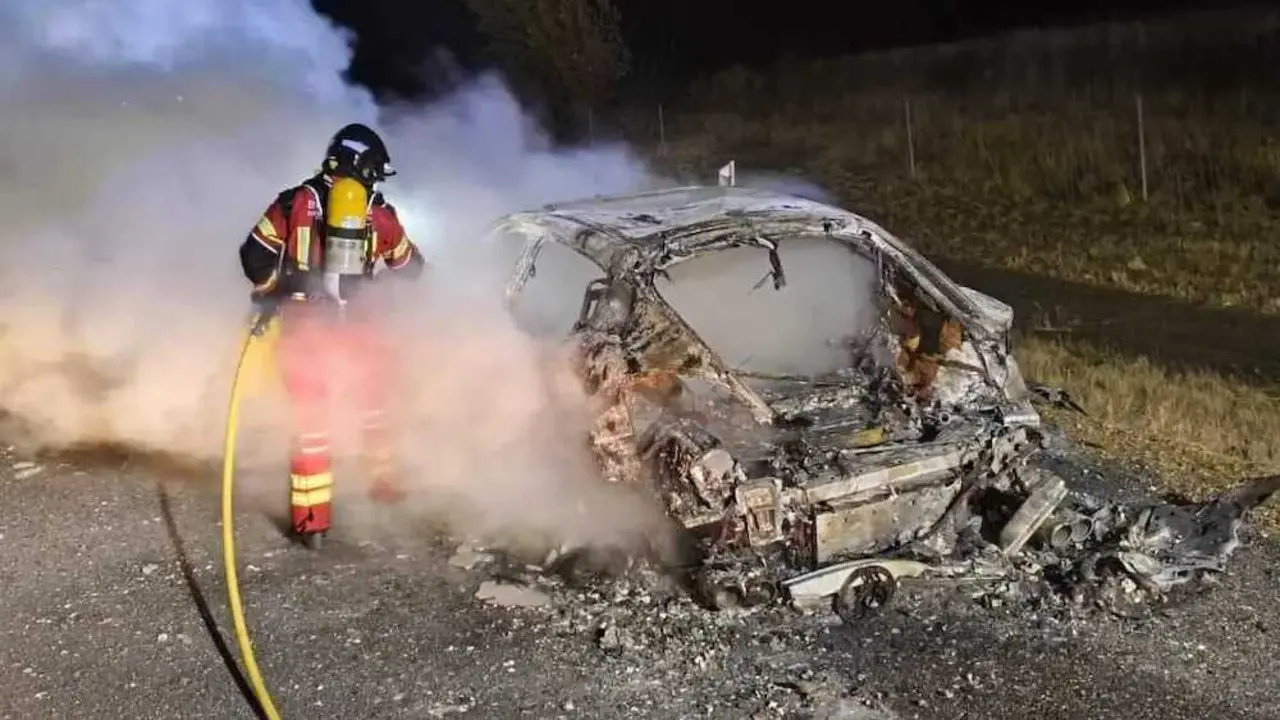 En la imagen de archivo un bombero extingue el fuego de un veh&iacute;culo incendiado y calcinado tras sufrir un accidente de tr&aacute;fico, aridendo,