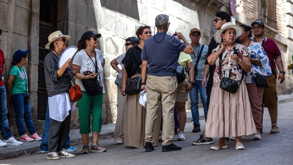 Unos turistas visiblemente acalorados atienden las explicaciones de un guía este viernes en Toledo. La ola de calor que azota España desde el pasado día 3 se prolongará hasta al menos el próximo jueves 14, según la última predicción de la Aemet, que ha vuelto a modificar su estimación para la duración de este episodio - EFE/Ismael Herrero